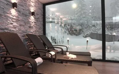 a room with chairs and a window with snow outside at Hotel ADLER Carezza in Nova Levante