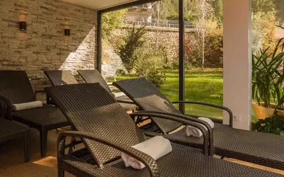 a row of chairs sitting on a porch with a view at Hotel ADLER Carezza in Nova Levante