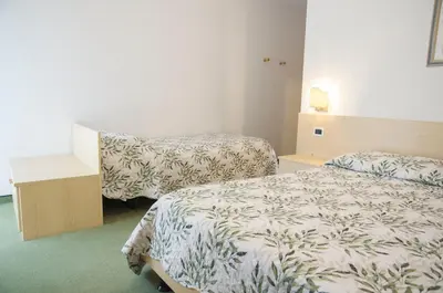 a hotel room with two beds and a table at Garnì Mariolina in Falcade