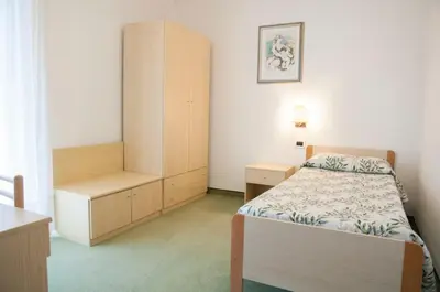 a small bedroom with a bed and a cabinet at Garnì Mariolina in Falcade