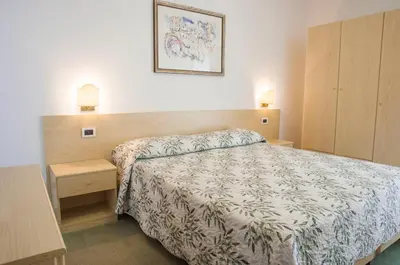 a bedroom with a bed and two night stands and two lamps at Garnì Mariolina in Falcade