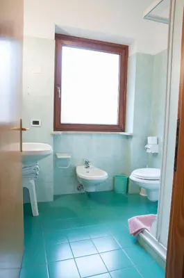 a bathroom with two sinks and a toilet and a window at Garnì Mariolina in Falcade