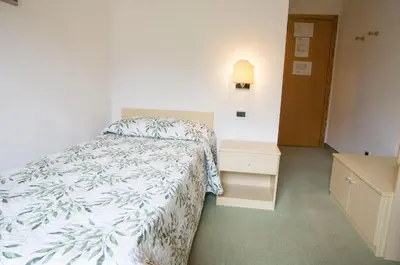 a small bedroom with a bed and a night stand at Garnì Mariolina in Falcade