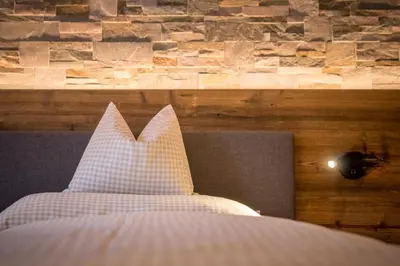 a bed with a white pillow and a stone wall at Appartment Hossler in Valdaora