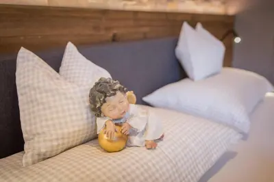 a small doll sitting on a bed with a teddy bear at Appartment Hossler in Valdaora