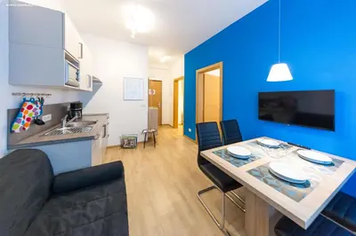 a kitchen and a dining room with a blue wall at City Charme Apartments in Bolzano