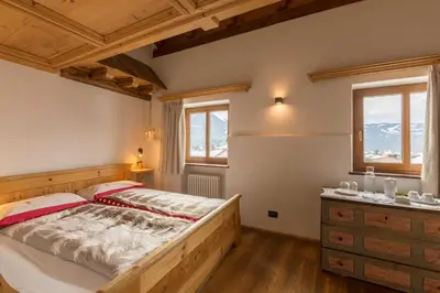 a bedroom with a bed and a dresser and windows at Historic Hotel Ristorante La Stua in Cavalese