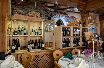 a restaurant with a table and bottles of wine at Historic Hotel Ristorante La Stua in Cavalese