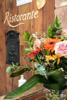a bouquet of flowers in a vase in front of a sign at Historic Hotel Ristorante La Stua in Cavalese