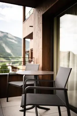 two chairs and a table on a balcony at Hotel Belaval in Selva di Val Gardena