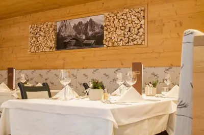 a table with white table cloth and wine glasses at Hotel Belaval in Selva di Val Gardena