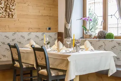 a dining room with a table with a white table cloth at Hotel Belaval in Selva di Val Gardena