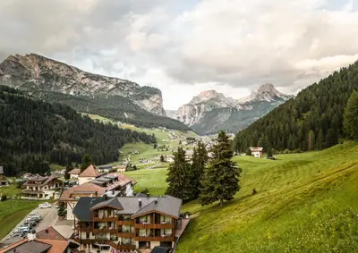 a village in a valley with mountains in the background at Hotel Belaval in Selva di Val Gardena