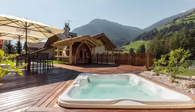 a hot tub on a deck with a house at Hotel Appartement Haus Gitschberg in Vandoies