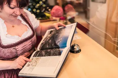 a woman reading a book next to a table at Hotel Appartement Haus Gitschberg in Vandoies