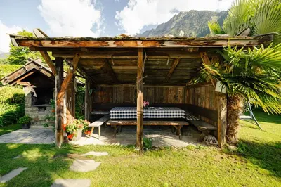 a wooden gazebo with a table in the grass at Hofer am Bach in Lagundo