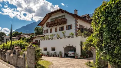 a large white house with a driveway at Hofer am Bach in Lagundo