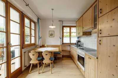 a kitchen with wooden cabinets and a table and chairs at Hofer am Bach in Lagundo
