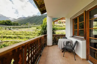 a balcony with a table and chairs and mountains at Hofer am Bach in Lagundo