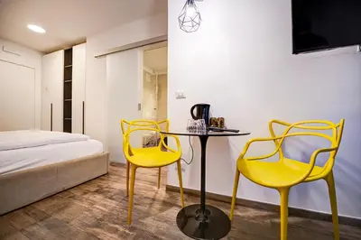 a room with two yellow chairs and a table and a bed at Taste Living in Merano