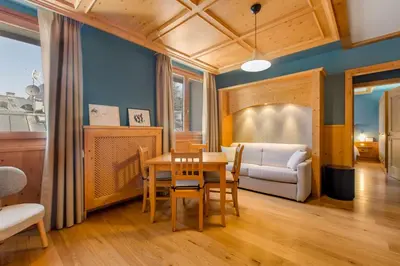 a dining room with a table and a couch at Radisson Residences Savoia Palace Cortina d’Ampezzo in Cortina dʼAmpezzo