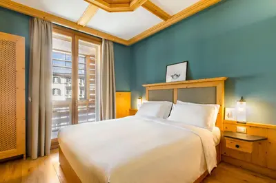 a bedroom with a large white bed with a window at Radisson Residences Savoia Palace Cortina d’Ampezzo in Cortina dʼAmpezzo
