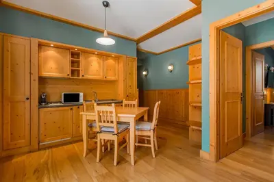 a kitchen with wooden cabinets and a table and chairs at Radisson Residences Savoia Palace Cortina d’Ampezzo in Cortina dʼAmpezzo