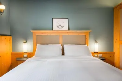 a bedroom with a large white bed with two lamps at Radisson Residences Savoia Palace Cortina d’Ampezzo in Cortina dʼAmpezzo