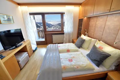 a bedroom with a bed and a tv and a window at Apartment Nogler Frieda in Selva di Val Gardena