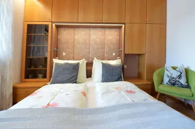 a bedroom with a bed and a green chair at Apartment Nogler Frieda in Selva di Val Gardena