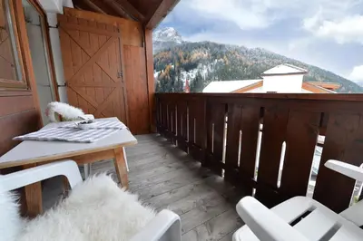 a balcony with white chairs and a table and a mountain at Apartment Nogler Frieda in Selva di Val Gardena