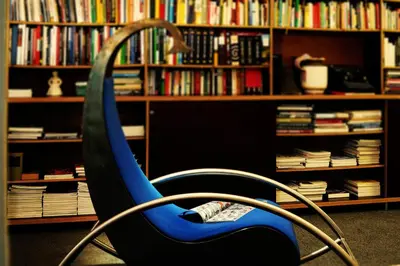 a blue chair in front of a book shelf with books at Villa Verdi Apartments in Merano