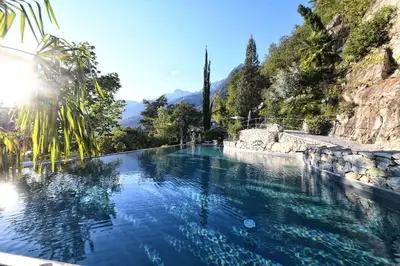a pool of water with trees and mountains in the background at Villa Verdi Apartments in Merano
