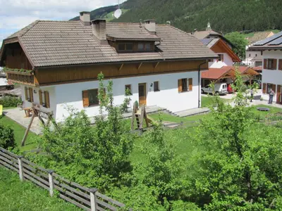 a large white house with a wooden roof at Appartements Hoferhof in Villabassa