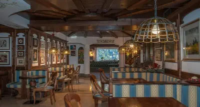 a restaurant with tables and chairs and a chandelier at Hotel Ai Pini in Vigo di Fassa