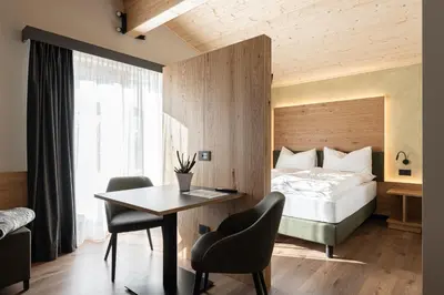 a hotel room with a bed and a table and chairs at Garnì La Violetta in Soraga