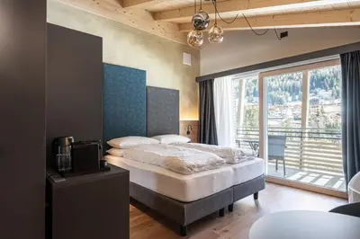 a bedroom with a bed and a large window at Garnì La Violetta in Soraga