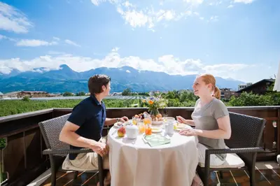 a man and woman sitting at a table on a balcony at Vettererhof in Lana