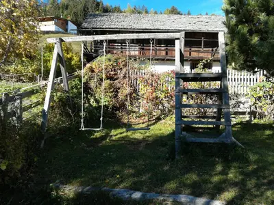 a swing in a garden next to a building at Bigraberhof in Valdaora