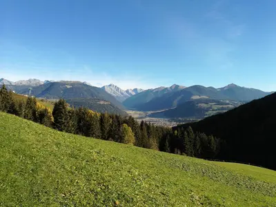 a green grassy hill with mountains in the background at Bigraberhof in Valdaora