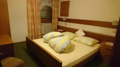 a bedroom with a bed with four pillows on it at Apartments Blumenheim in Castelrotto