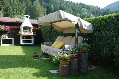 a chair under an umbrella in a yard at Casa Aurora -Altopiano di Pinè in Bedollo