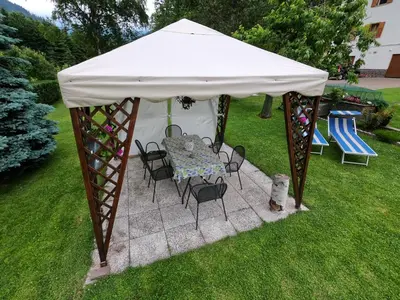 a white tent with chairs and a table in a yard at Casa Aurora -Altopiano di Pinè in Bedollo