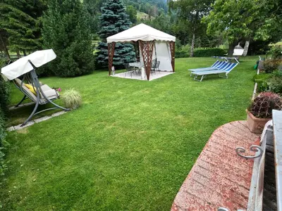 a yard with a gazebo and two chairs and a table at Casa Aurora -Altopiano di Pinè in Bedollo