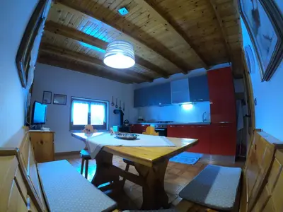 a kitchen with a wooden table and a dining room at Casa Aurora -Altopiano di Pinè in Bedollo