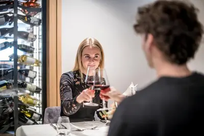 a woman sitting at a table holding a glass of wine at Sporthotel Zoll in Vipiteno