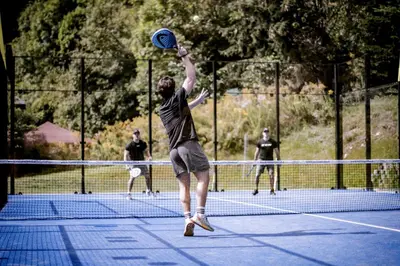 a man jumping up to catch a frisbee on a tennis court at Sporthotel Zoll in Vipiteno