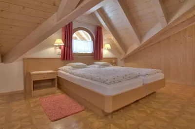 a bedroom with a large bed in a attic at Villa Martha ex Garnì Oskar in Corvara in Badia