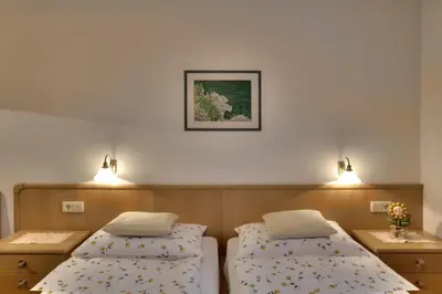 a room with two beds and two lights on the wall at Villa Martha ex Garnì Oskar in Corvara in Badia