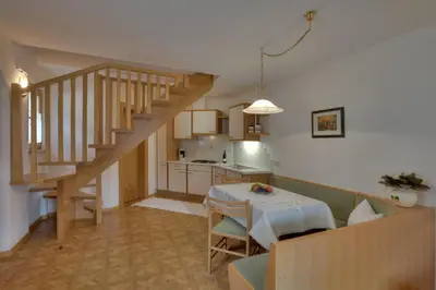 a kitchen and dining room with a table and a staircase at Villa Martha ex Garnì Oskar in Corvara in Badia